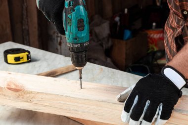 Marangoz bir vidayı elektrikli tornavidayla ağaca çevirir, erkek eli de yakın çekim tornavidayla. Tahtayla çalış.