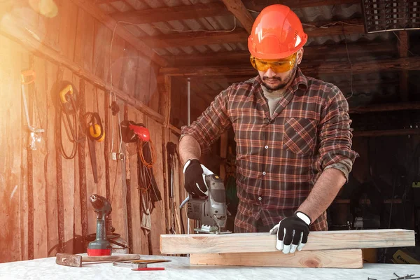 Мужчина-плотник режет деревянный луч электрической пилой, мужские руки электрической пилой крупным планом. Работа с деревом . — стоковое фото