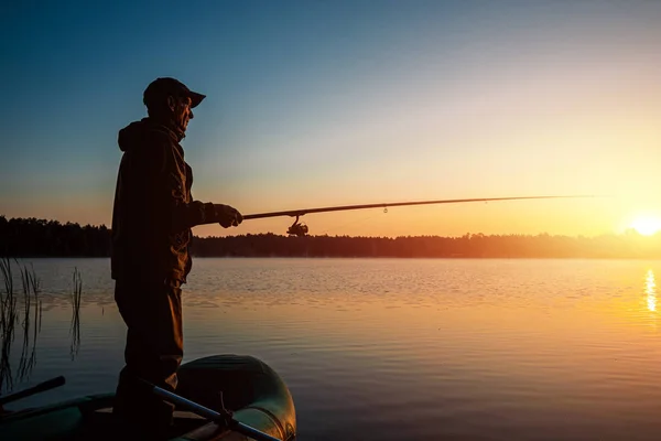 Pescatore maschio all'alba sul lago cattura una canna da pesca. Pesca concetto di vacanza hobby. Copia spazio . — Foto Stock