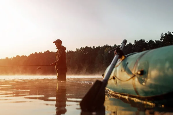 새벽에 호수에 고무배를 타고 새벽에 낚시를 하는 어부가 있었습니다. 낚시 취미 휴가 개념. 복사 공간. — 스톡 사진