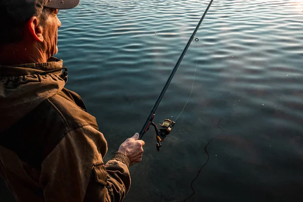 Un pêcheur mâle sur le lac est debout dans l'eau et pêche pour une canne à pêche. Loisirs de pêche concept de vacances. Espace de copie. — Photo