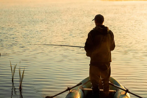 Pescatore maschio all'alba sul lago cattura una canna da pesca. Pesca concetto di vacanza hobby. Copia spazio . — Foto Stock