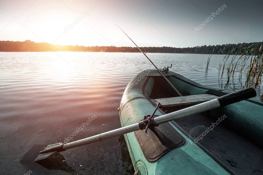 Inflatable boat on the lake at sunrise. Fishing hobby vacation concept. Copy space