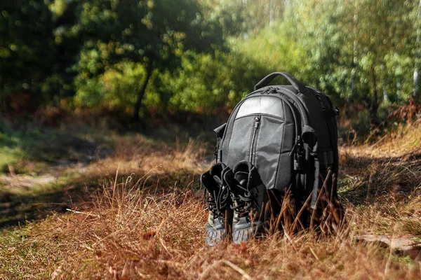 Camping backpack and boots on a background of summer nature. Trekking and camping adventures, hiking, hiking, traveling.