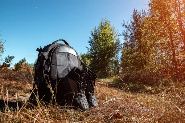 Camping backpack and boots on a background of summer nature. Trekking and camping adventures, hiking, hiking, traveling.