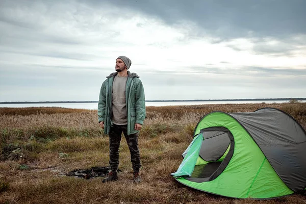 Un homme barbu près d'une tente de camping en vert sur le fond de la nature et du lac. Le concept de voyage, tourisme, camping . — Photo