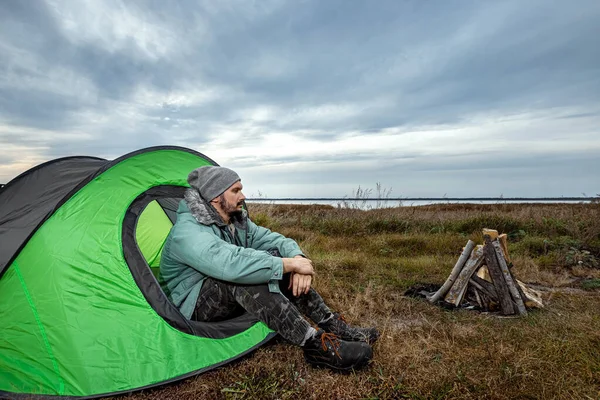 Un barbu campe dans une tente sur fond de nature et de lac. Le concept de voyage, tourisme, camping . — Photo