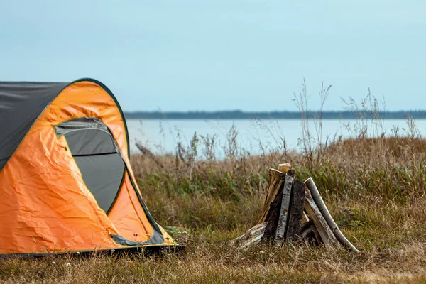 Zeltlager in Orange vor dem Hintergrund der Natur und des Sees. das Konzept von Reisen, Tourismus, Zelten. — Stockfoto