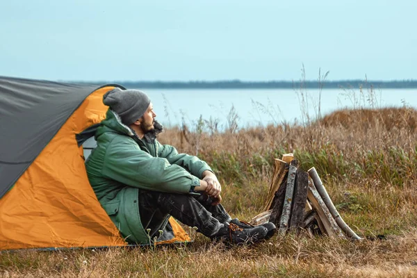 Un barbu campe dans une tente sur fond de nature et de lac. Le concept de voyage, tourisme, camping . — Photo
