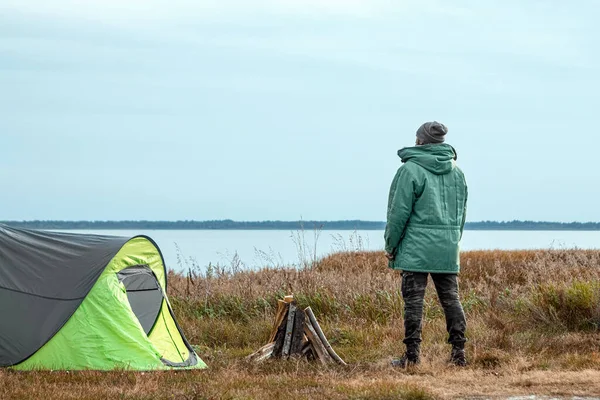 Un homme barbu près d'une tente de camping en vert sur le fond de la nature et du lac. Le concept de voyage, tourisme, camping . — Photo