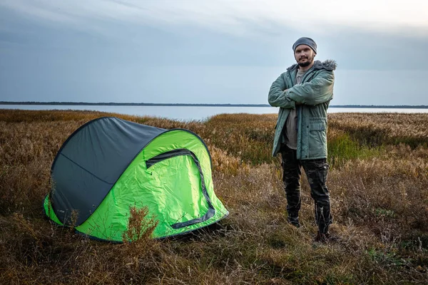 Un homme barbu près d'une tente de camping en vert sur le fond de la nature et du lac. Le concept de voyage, tourisme, camping . — Photo