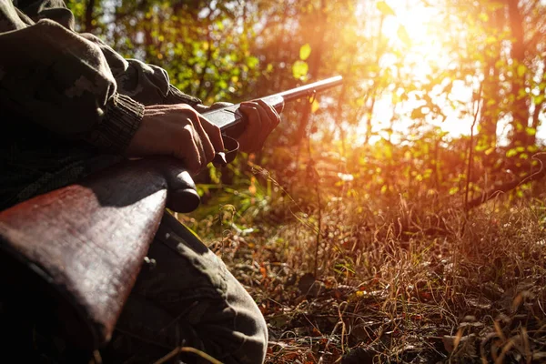 Um caçador com uma arma nas mãos em roupas de caça na floresta de outono close-up. O período de caça, a época de outono está aberta, a busca de presas . — Fotografia de Stock