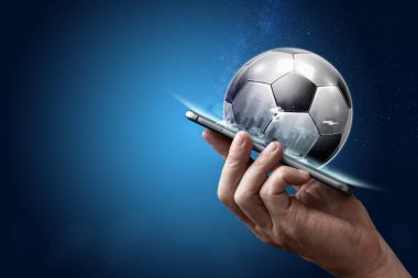 Elinde mavi arka planda 3D futbol topu olan akıllı bir telefon. Bahisler, spor bahisleri, bahisçiler. Karışık ortam