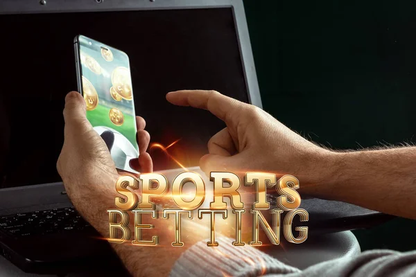 Smartphone en la mano letras de oro Deportes Apuestas en el fondo del ordenador portátil. Apuestas, apuestas deportivas, casa de apuestas. Medios mixtos — Foto de Stock