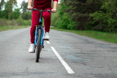 Bacakların yakın çekimde bisikletin pedallarında, ormanda yolda giderken. Sağlıklı yaşam tarzı konsepti, kardiyo eğitimi. Kopyalama alanı