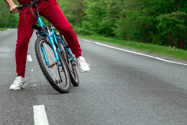 トラックスーツの男は森の中の道路上の自転車の隣に立っている 健康的なライフスタイル 心臓トレーニングの概念 コピースペース — ストック写真