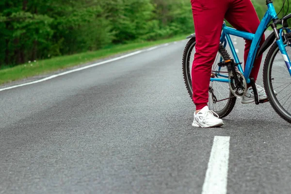 トラックスーツの男は森の中の道路上の自転車の隣に立っている 健康的なライフスタイル 心臓トレーニングの概念 コピースペース — ストック写真