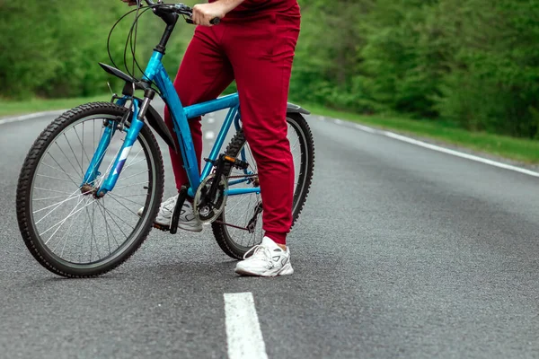 トラックスーツの男は森の中の道路上の自転車の隣に立っている 健康的なライフスタイル 心臓トレーニングの概念 コピースペース — ストック写真