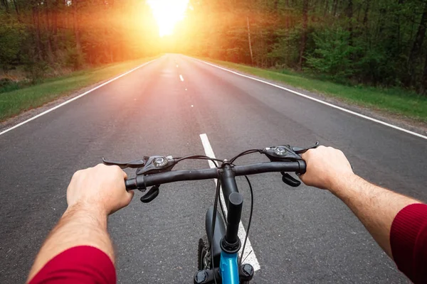 森の中の道路に乗って自転車のハンドルバーに男性の手 健康的なライフスタイル 心臓トレーニングの概念 コピースペース — ストック写真