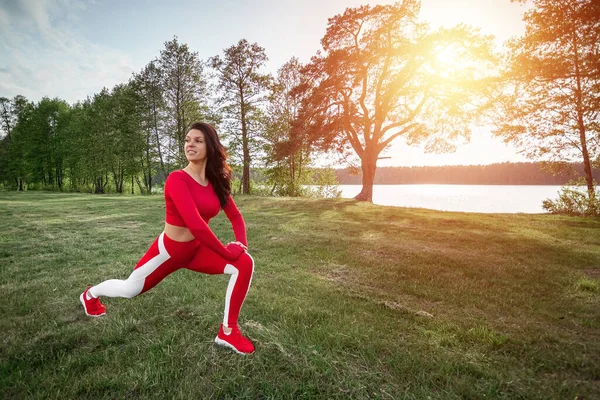 Beautiful girl in a sports suit does stretching before sports exercises in nature, fresh air. The concept of a healthy lifestyle, fitness. Copy space