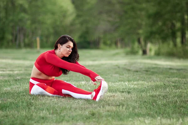 Beautiful girl in a sports suit does stretching before sports exercises in nature, fresh air. The concept of a healthy lifestyle, fitness. Copy space