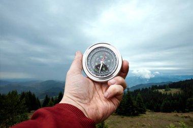 Erkek eli ve gümüş pusula dağ manzarasının arka planında. Seyahat, yürüyüş, yardım, arama, tatil kavramı. Boşluğu kopyala