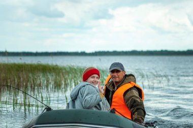 Baba ve oğlu gölde bir motorlu tekneye biniyor. Aile kavramı, yaz tatili, nesil. Boşluğu kopyala