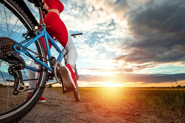 自転車でのスポーツトレーニング 夕日の背景にスポーツスーツの美しい女の子 健康的なライフスタイル 心臓トレーニング 身体活動の概念 スペースのコピー — ストック写真