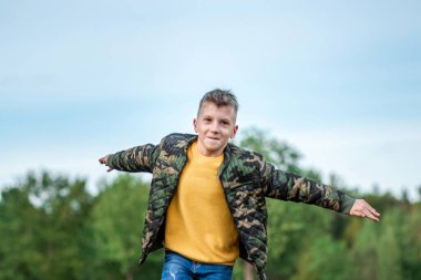 Kollarını yeşilliğin arka planına uzatmış bir çocuk tarlada koşuyor. Hayallerin konsepti, meslek seçimi, pilot, çocukluk. Boşluğu kopyala