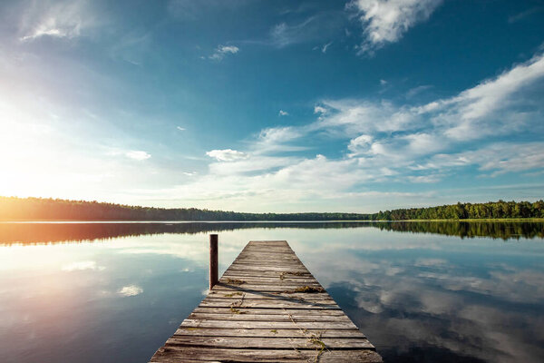 Wooden pier on the background of a beautiful lake summer dawn landscape. Copy space