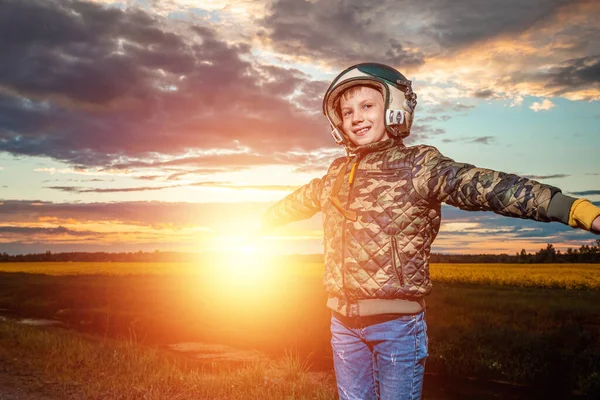 A boy in a pilot\'s helmet on a sunset background. Dream concept, choice of profession, game. Copy space