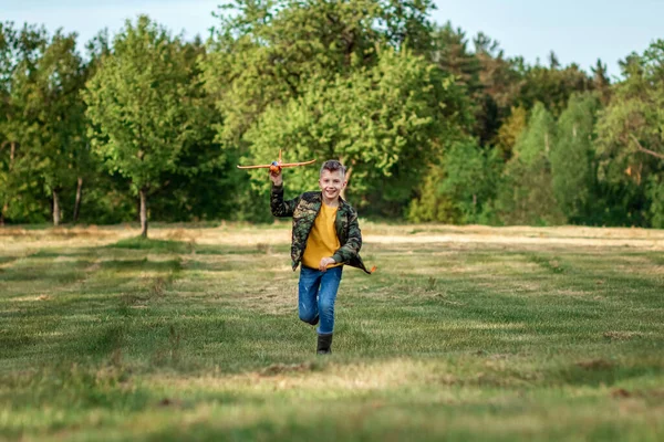 一个男孩跑过田野 在绿树成荫的背景下发射了一架玩具飞机 梦想的概念 职业的选择 飞行员 复制空间 — 图库照片