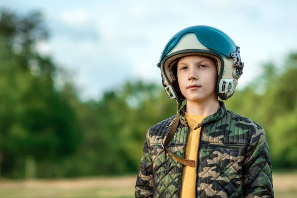 A boy in a pilot\'s helmet on a background of greenery. Dream concept, choice of profession, game. Copy space