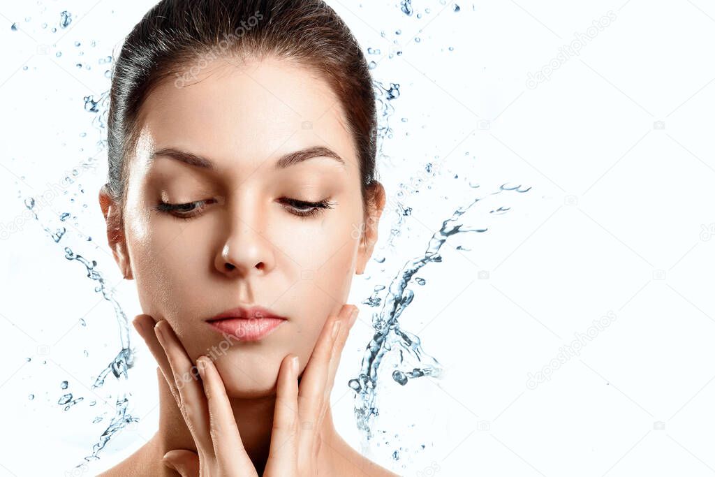 Portrait of a beautiful girl on a white background with splashes of water. Spa treatments. The concept of skin care, hydration, beauty. Copy space