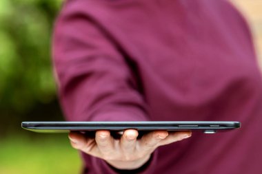 Bir tablet, bir harita çantası avucunun içinde duruyor, yakın plan elinde.