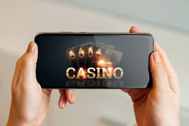 Elinde iskambil kağıtları olan bir akıllı telefonun elinde siyah altın kaplama bir kumarhane. Online kumar, online kumarhane kavramı. Boşluğu kopyala