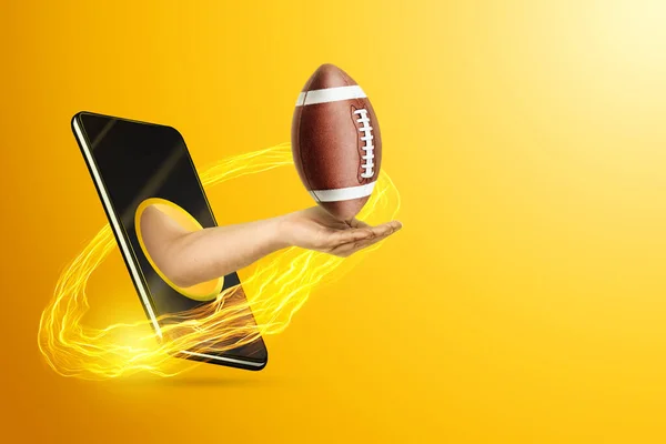 Ruka Drží Americký Fotbalový Míč Přes Smartphone Žlutém Pozadí Koncept — Stock fotografie