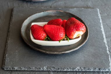 Çilek bir plaka üzerinde. Gri ve rustik arka plan