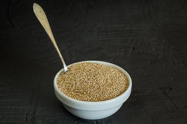 Quinoa tohumları bir kase ve kaşık. Sağlıklı, protein açısından zengin karbonhidratlar. Rustik ve koyu arka plan