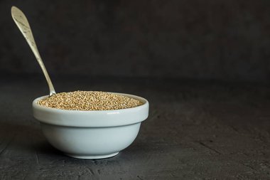 Quinoa tohumları bir kase ve kaşık. Sağlıklı, protein açısından zengin karbonhidratlar. Rustik ve koyu arka plan