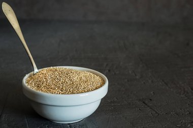 Quinoa tohumları bir kase ve kaşık. Sağlıklı, protein açısından zengin karbonhidratlar. Rustik ve koyu arka plan