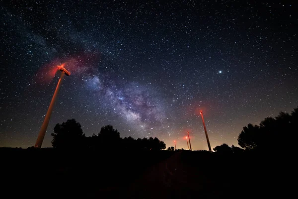 Long exposure night photography with the Milky Way and its galactic center on a wind power mill