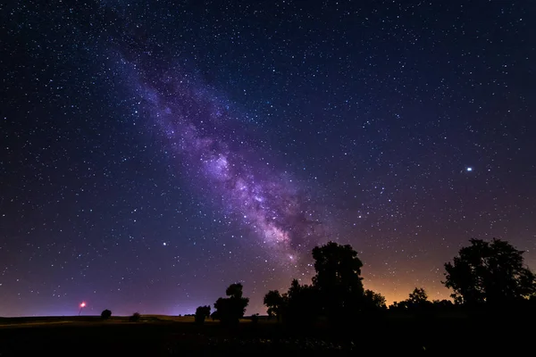 Long exposure photograph of the Milky Way and its galactic center on a field near the city of Madrid in Spain.