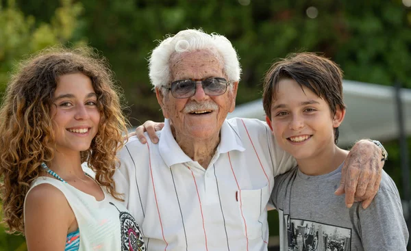 Great-grandfather at 100 years of age, and two of his grandchildren, boy and girl