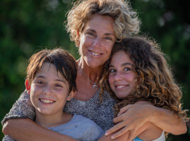 Anne, oğlu ve kızı tatil sırasında bir bahçede portresi
