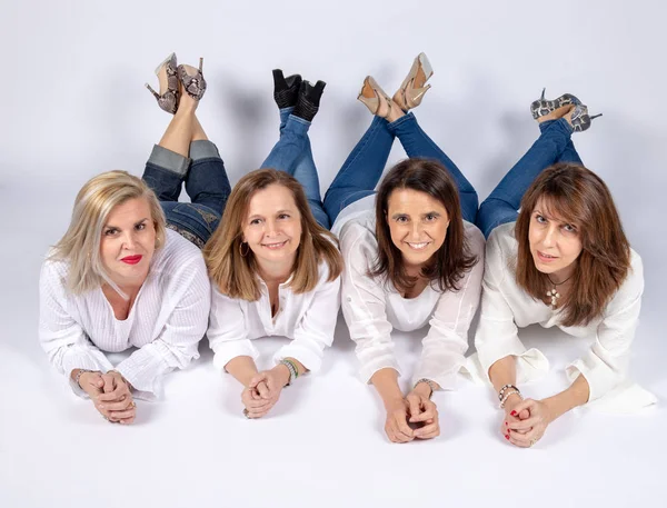 Photographic session in a studio to four friends lying on the floor with white background.
