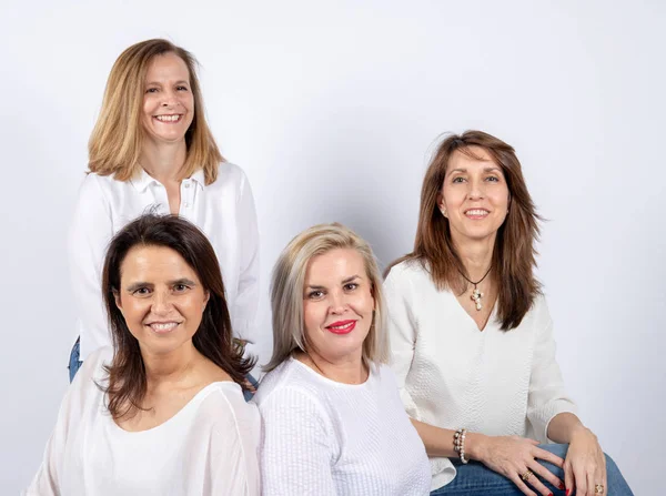 Grup 4 kadın, arkadaşlar, bir top üzerinde oturan beyaz arka plan ile bir stüdyoda fotoğraf oturumunda eğleniyor orta yaşlı