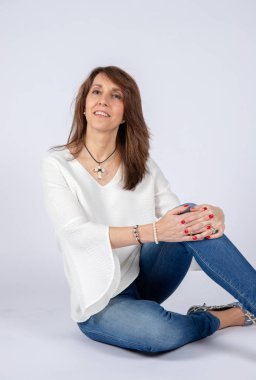 Fotoğraf stüdyosu oturum katta oturan ve kot pantolon ve beyaz gömlek giymiş 50 yaşında bir kadın için.