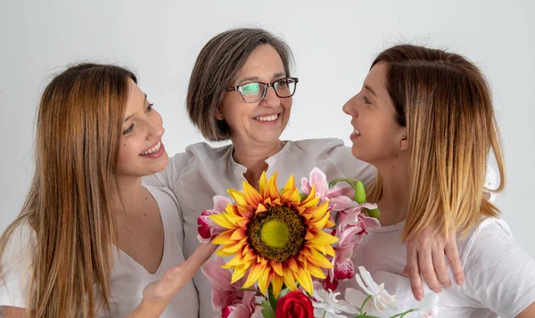 Madre y dos hermanas gemelas disfrutan en actitud muy divertida con un gran girasol en sus manos — Foto de Stock