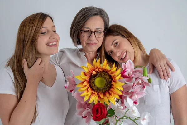 Madre y dos hermanas gemelas disfrutan en actitud muy divertida con un gran girasol en sus manos — Foto de Stock